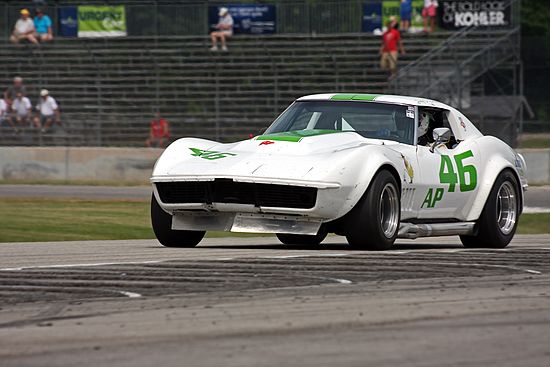 White Racing corvette on track, vintage Chevrolet Corvette at speed.