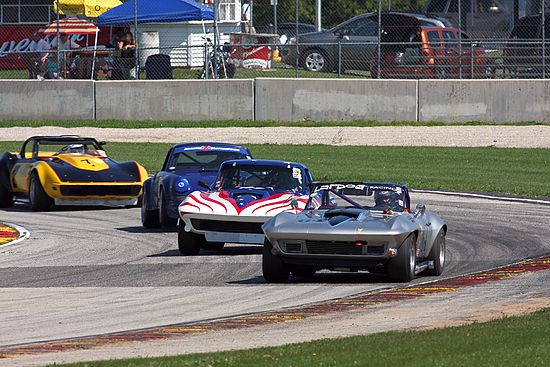 Group of four vintage Corvettes, racing at speed.